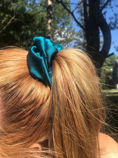 A teal scrunchie holding up someone's auburn hair.