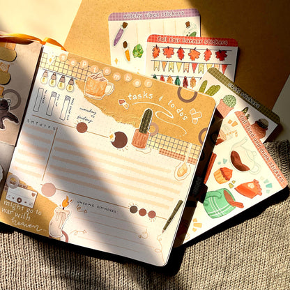 A square notebook decorated with various stickers. The page is a bullet journal weekly spread for September.
